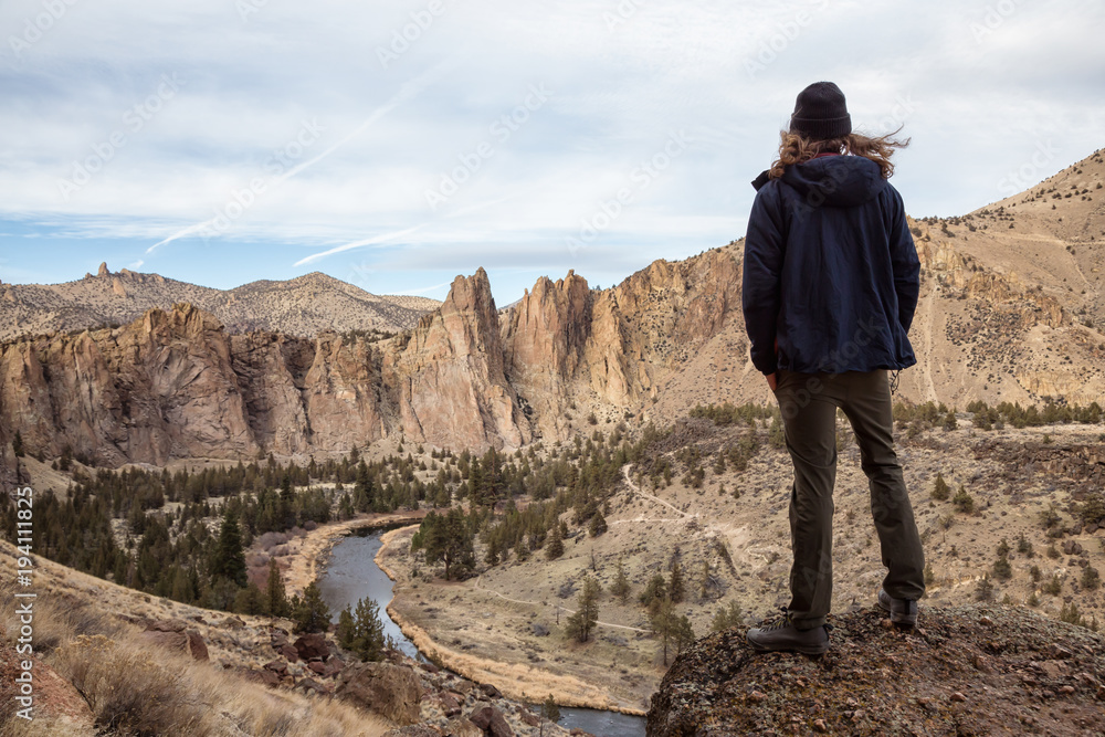 Naklejka premium Man enjoying the Beautiful American Mountain Landscape during a vibrant winter day. Taken in Smith Rock, Redmond, Oregon, America. Concept: Adventure, Holiday and Travel