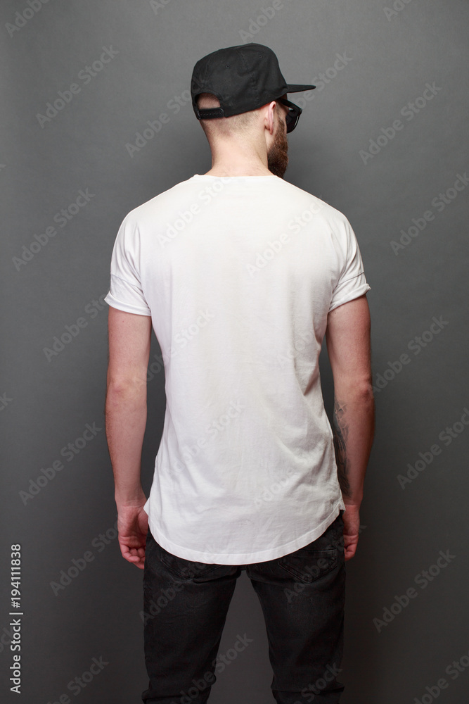Hipster handsome male model with beard wearing white blank t-shirt with space for your logo or design over gray background Hipster handsome male model with beard wearing white blank t-shirt with space for your logo or design over gray background