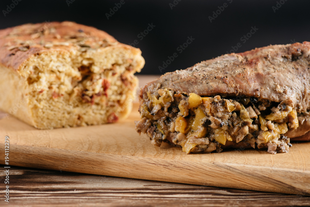 Pumpkin muffin and baked meat roll with a wooden stick on a black background