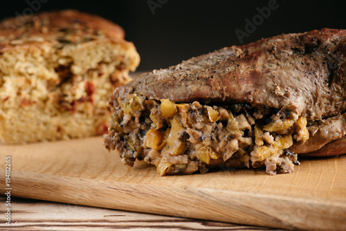 Pumpkin muffin and baked meat roll with a wooden stick on a black background