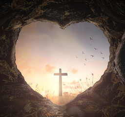 Christian cross seen through a heart-shaped cave entrance, conceptual image of Jesus resurrection, divine light, and hope