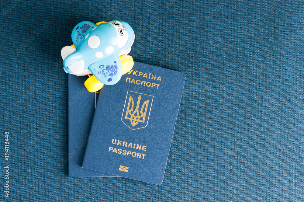 Obraz premium Ukrainian passport on a blue background with a toy airplane.