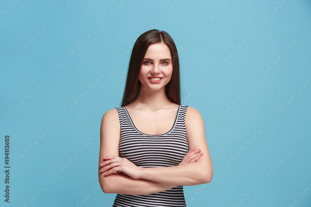 The happy woman standing and smiling against blue background. The happy woman standing and smiling against blue background.