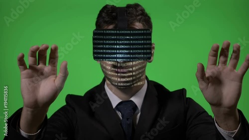 Male engineer dressed in suit and tie using futuristic virtual reality technology to type and check blockchain data on green screen photo