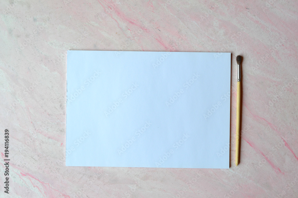 The sheet of white paper and brush on the textured desk. Top view. Tools for painting. The sheet of white paper and brush on the textured desk. Top view. Tools for painting.