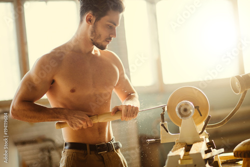 wood lathe, lathe naked operator working a wood pestle photo