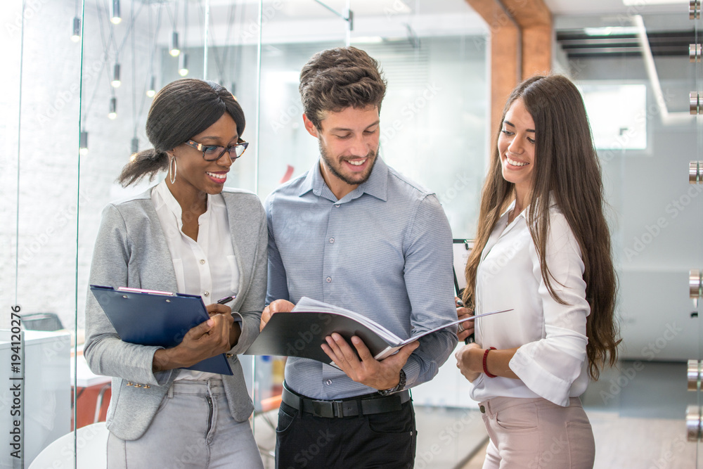 Fototapeta premium Three smiling business people discussing document in the modern office.