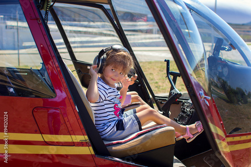 The girl sits at a helicopter steering wheel