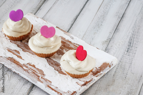 Three homemade raw capkake with cashew cream on a wooden white background. Style rutsik photo