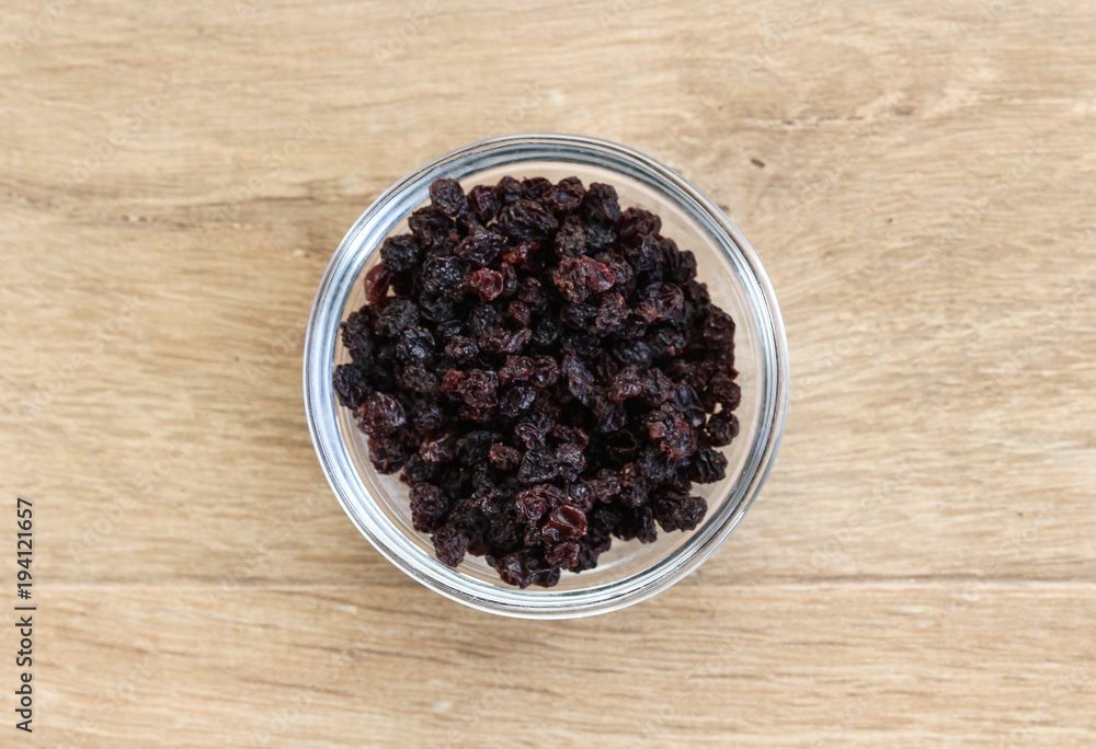 bowl with black dry currants raisins on wooden background bowl with black dry currants raisins on wooden background