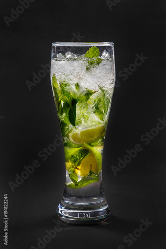 Summer drink with lime and mint, ice on isolated black background. Direct perspective, cool, refreshing