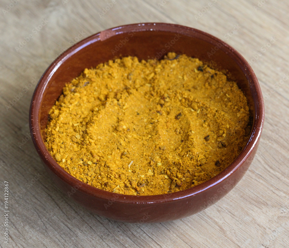 Stone bowl with yellow turmeric curry powder on wooden background Stone bowl with yellow turmeric curry powder on wooden background