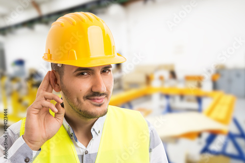 Factory worker making can't hear you because of noise gesture.