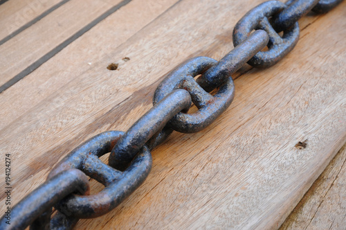 Metal anchor chain on a teak deck of a classic sailing boat