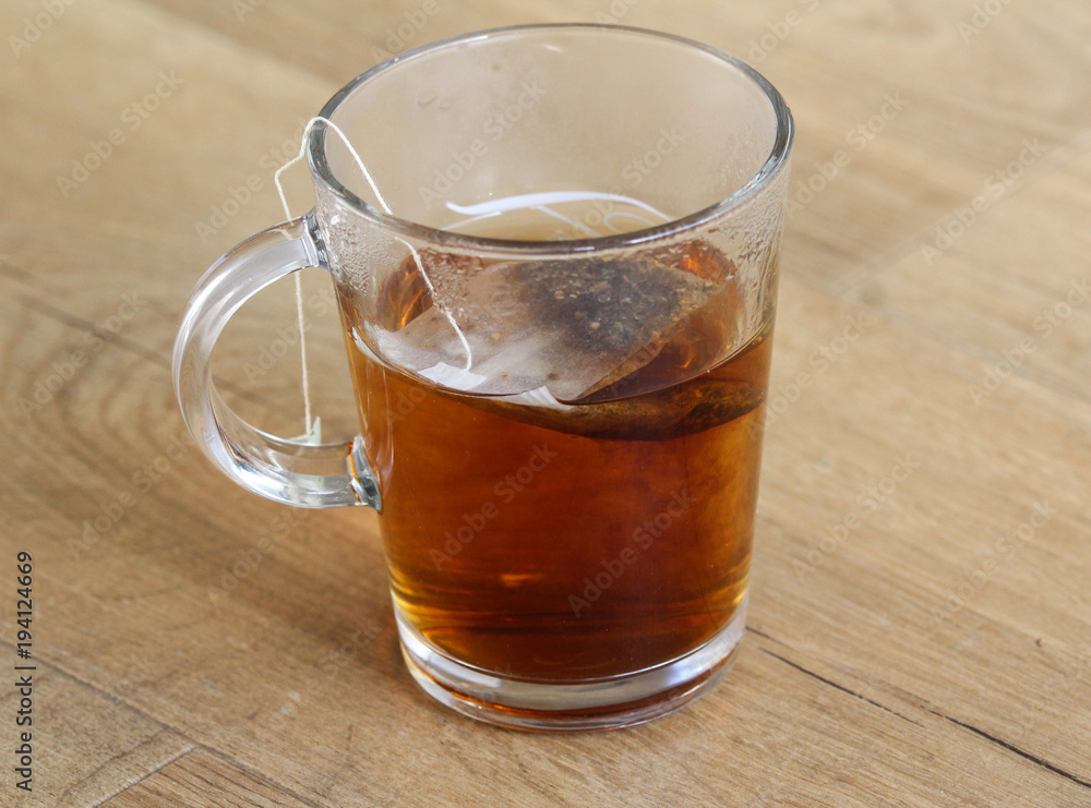 Glass of Moroccan mint tea with tea bag on wooden background Glass of Moroccan mint tea with tea bag on wooden background