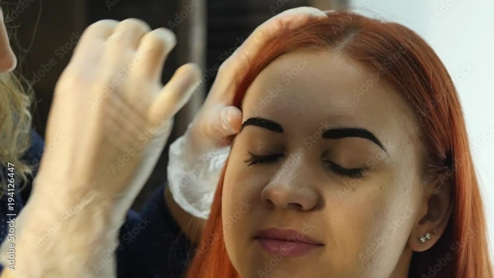 Professional make-up artist drawing eyebrows of beautiful client. Beauty and fashion concept Professional make-up artist drawing eyebrows of beautiful client. Beauty and fashion concept