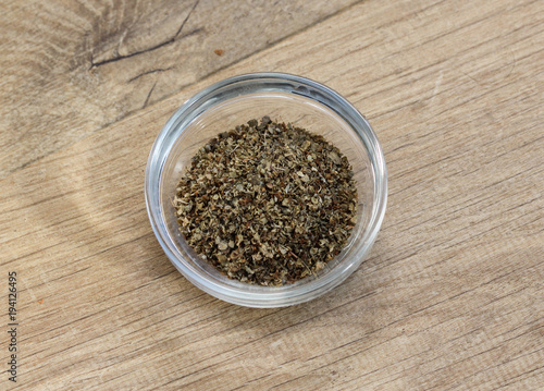 Glass bowl with fresh sliced marjoram herbs on wooden background