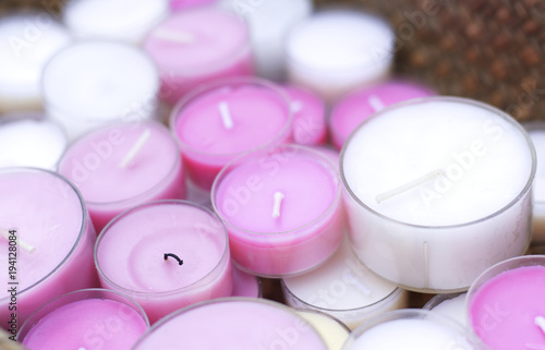 Closeup of many pink and white candles on a wooden basket pattern
