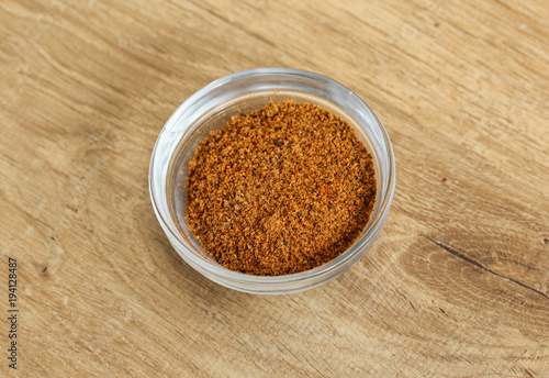 Glass bowl with hot cajun seasoning on wooden background