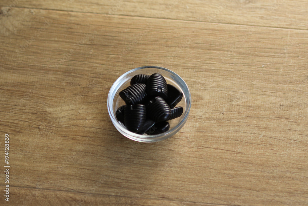 Glass bowl with honey liquorice on wooden background