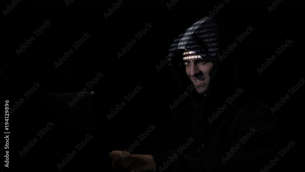 Young nonconformist teenager hacker organizing malware attack on global scale while the binary code is projected on his face Young nonconformist teenager hacker organizing malware attack on global scale while the binary code is projected on his face