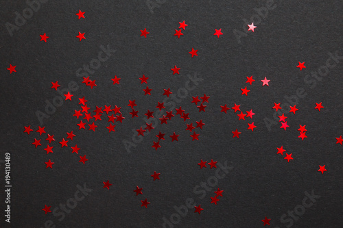 Confetti. Frame made of colored red star confetti front of black background. Copy space