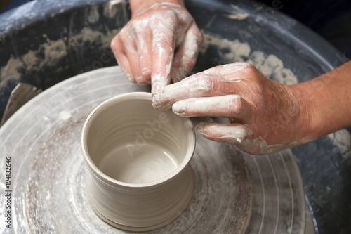 A lady ceramics artist at work in her home pottery studio, forming a mug shape