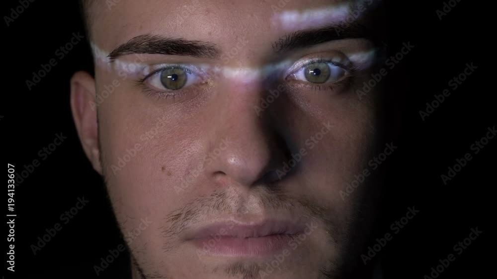 Portrait of a brilliant teenager with green eyes watching the hacking process on screen while the code is reflected on his face Portrait of a brilliant teenager with green eyes watching the hacking process on screen while the code is reflected on his face