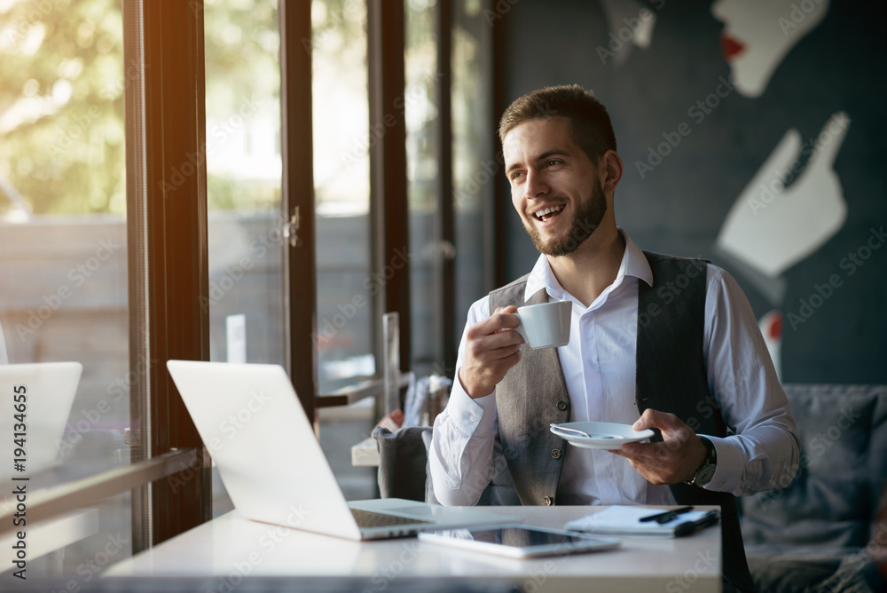 Fototapeta premium Young man drawing template for the web site associated with digital marketing, current trends and tendencies of UX / UI design. Businessman who rules his company remotely, like a freelancer