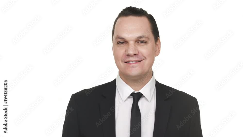 Portrait of content businessman 30s in black business suit smiling and expressing gladness, over white background in studio. Concept of emotions Portrait of content businessman 30s in black business suit smiling and expressing gladness, over white background in studio. Concept of emotions