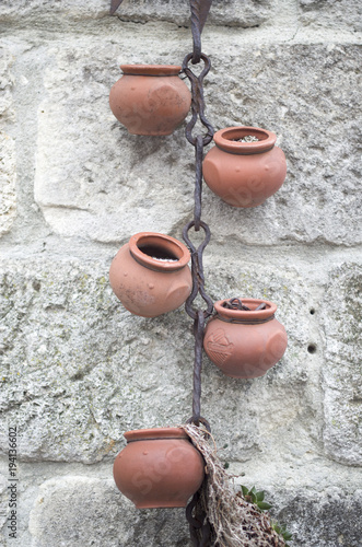 A decorative element of ceramic pots and a rusty chain on wall photo