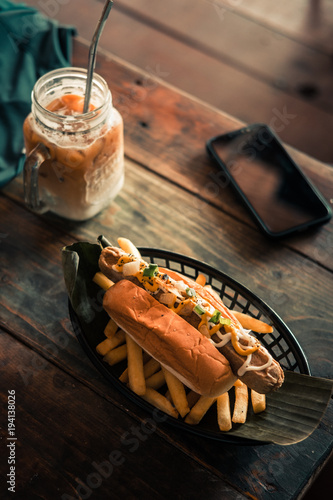 Delicious hotdog served on a rustic wooden table. Dark food photography concept. Vertical photo