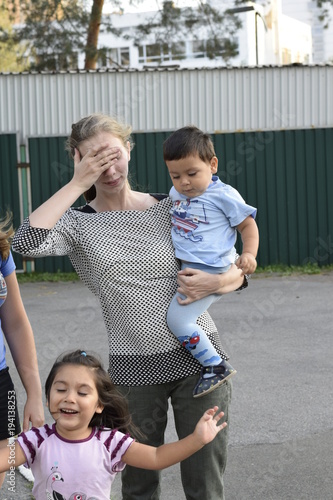 уставшая кавказская мать на прогулке с латинскими детьми  