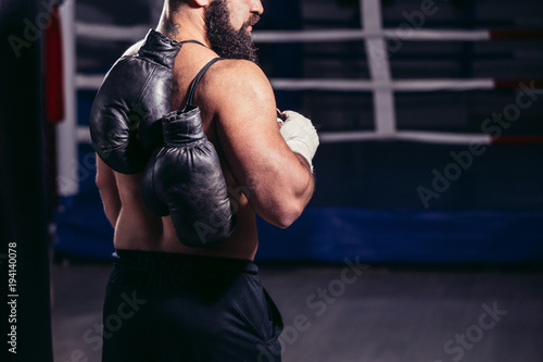 Young muscular man boxer. Boxing gloves slung over his shoulder