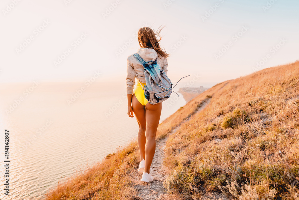 Young attractive woman in yellow clothes and in white sneakers in nature. Woman with perfect body