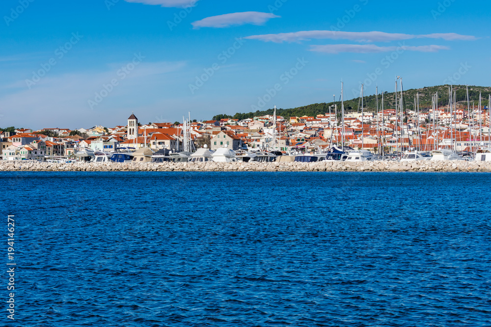 Beautiful seascape view of a small mediterranean town with a marina with moored sailing boats and yachts, Croatia