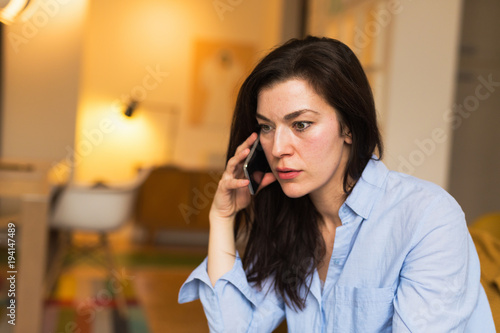 Worried woman talking on the phone at her home