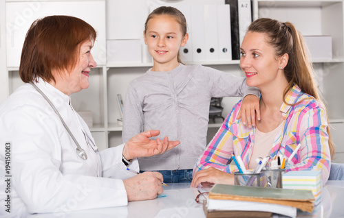 Little girl and mother with mature medical worker