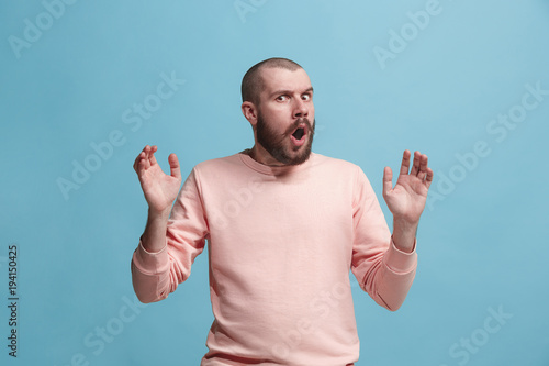 Quadro su tela The young attractive man looking suprised isolated on blue