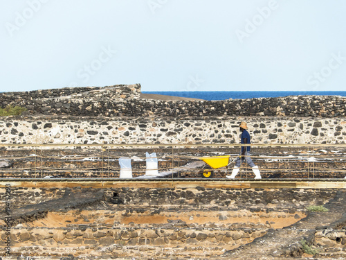 Worker harvesting salt in a saline in the island Fuerteventura Canary Islands. photo