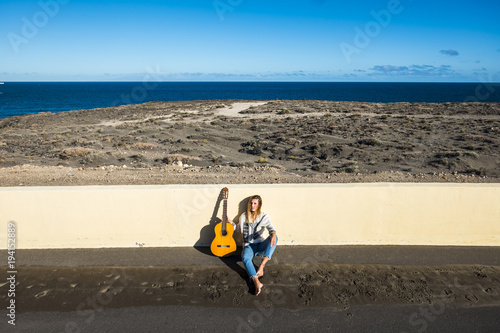 young girl with guitar sitdown near the ocean in tenerife photo