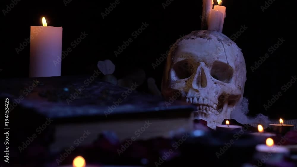 Skull with candles and an old book on the table, slider shooting Skull with candles and an old book on the table, slider shooting