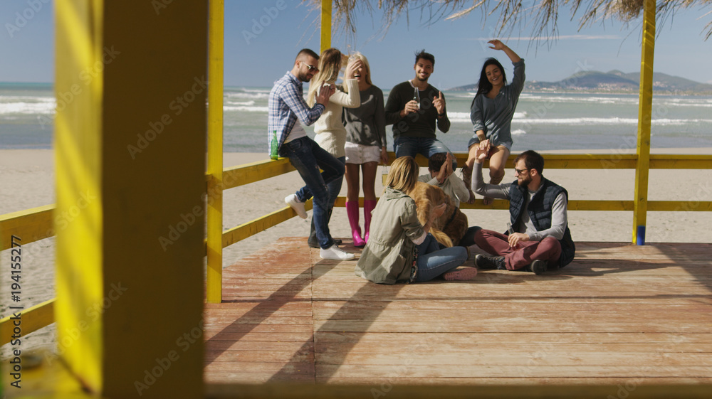 Group of friends having fun on autumn day at beach