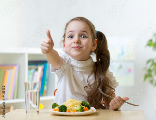Smiling child girl eats hea...