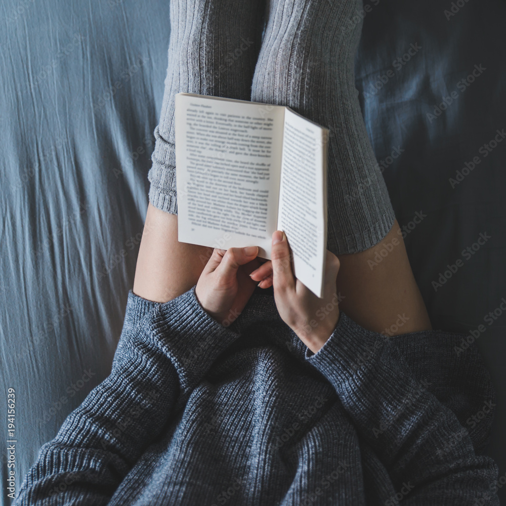 Obraz premium woman read book in bed with gray sheets.