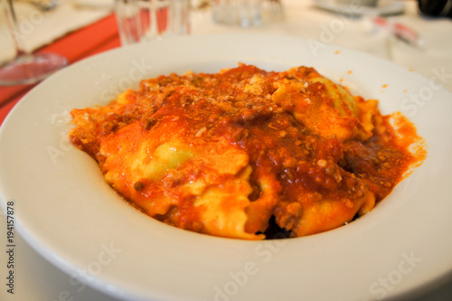 Pasta ravioli with tomato sauce, pepper, olive oil and Parmesan cheese, a meal in a white plate.