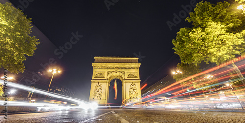 Impressive Arc de Triomphe and car lights at night