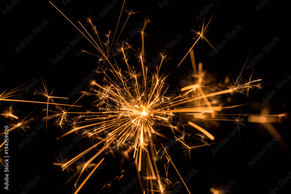 Burning sparkler with sparks bursting in air