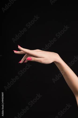 beautiful woman hand with pink manicure on the nails isolated on black.