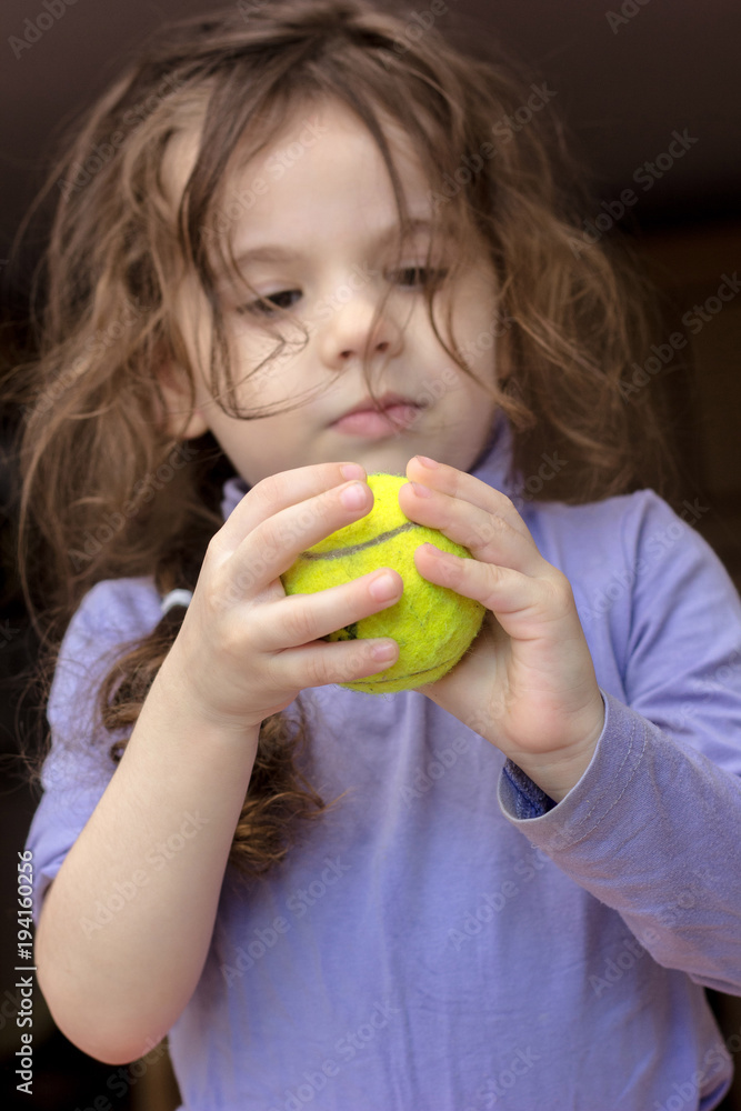 Young kid girl holding tennis ball in hands. Young kid girl holding tennis ball in hands.